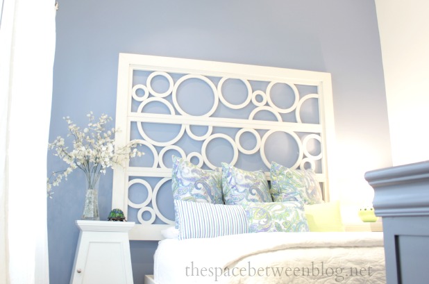 white screen hung on a wall and used as a headboard on purple walls