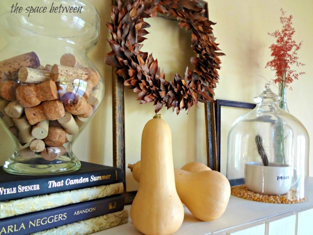 squash, corks, books and a leaf wreath decorating a diy floating mantel for fall